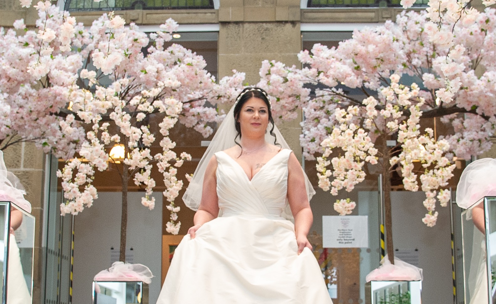Bride in a full ivory gown and veil framed by blossom trees