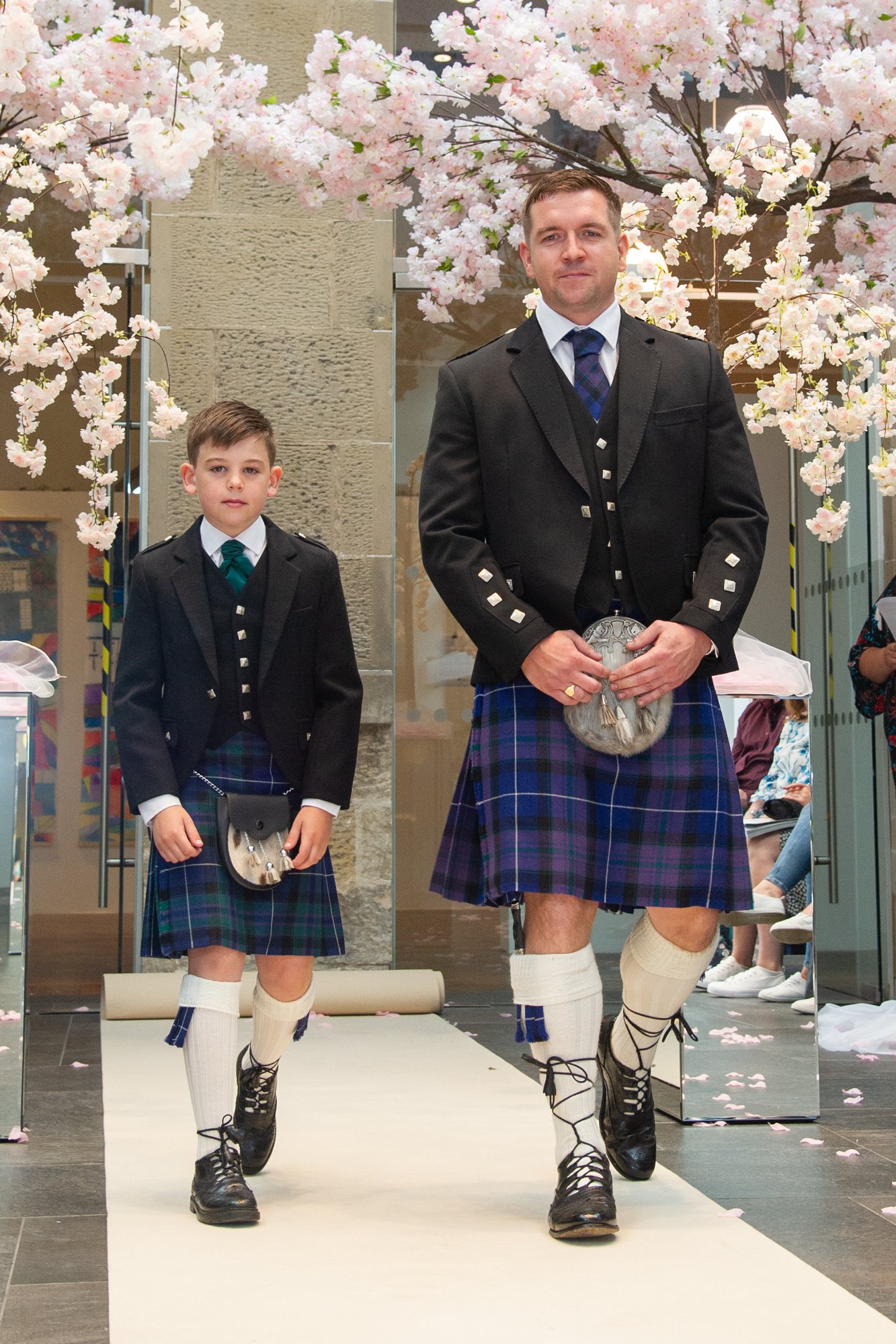 Man and boy in Highland dress walking the catwalk at the Moray Wedding Show