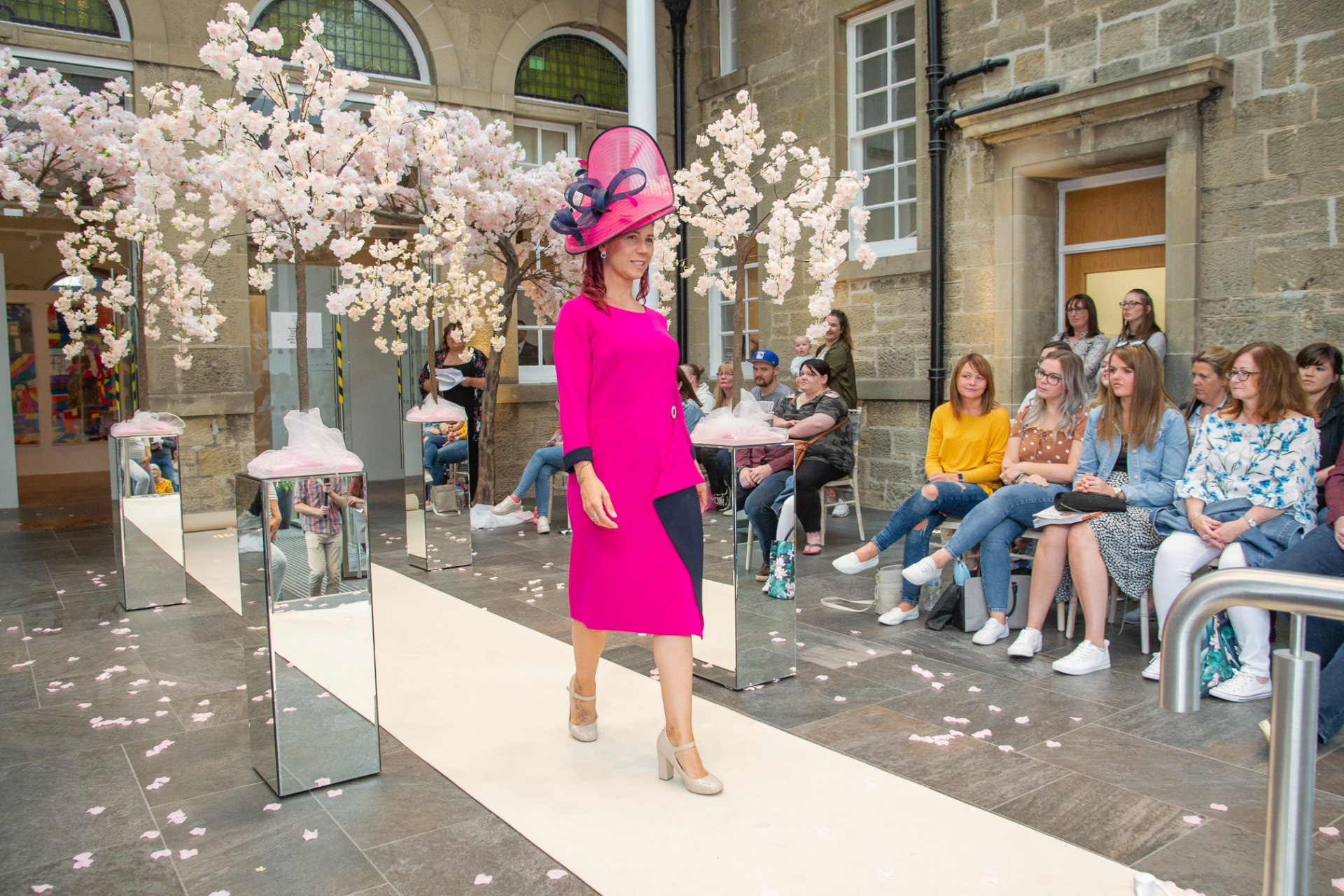 Model in a bright pink dress and hat on the catwalk at the Moray Wedding Show